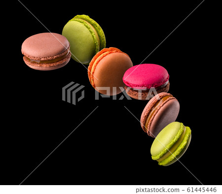Flying french colorful macaroons on wooden table isolated on black 61445446