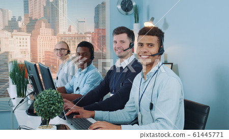 Diverse team of call center customers looking to the camera and smiling after talking to the international clients on phones Diverse team of call center customers looking to the camera and smiling after talking to the international clients on phones 61445771