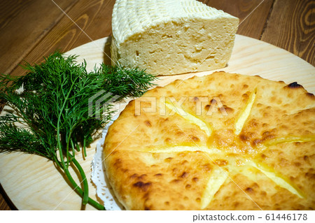 Ossetian pie with cheese and dill. A traditional dish of the Caucasian fish soup. Dough product with filling on the background of an old wooden table. The concept of tasty and healthy food. 61446178