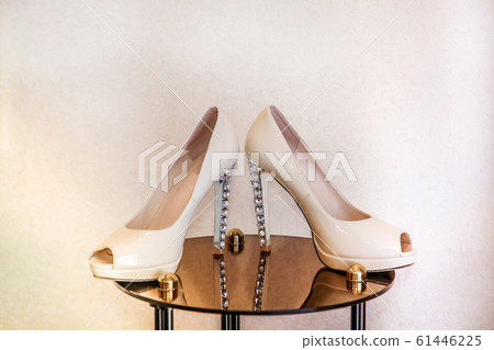 Wedding shoes with high heels stand on a mirrored table and decorated with precious stones Wedding shoes with high heels stand on a mirrored table and decorated with precious stones 61446225