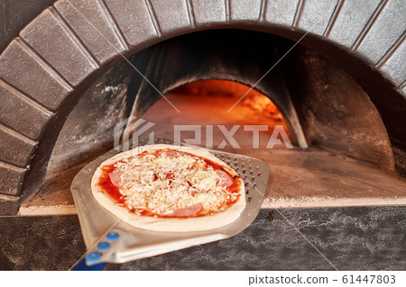 Raw billet for baking tasty margherita pizza in Traditional wood oven in Naples restaurant, Italy. Original neapolitan pizza. Red hot coal. 61447803