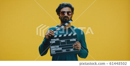 Bored man clapping clapperboard 61448502