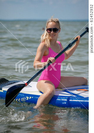 Young athletic woman in bright pink swimsuit doing Young athletic woman in bright pink swimsuit doing 61452932