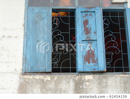 An old blue wooden window on an old peeling wall. 61454139