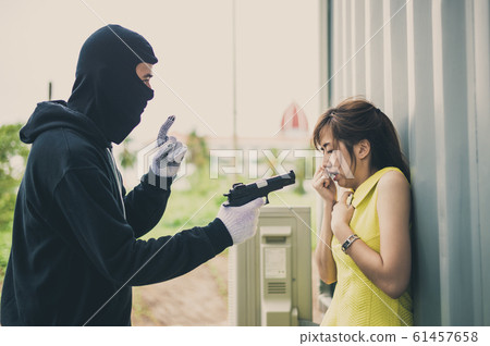Bandit wear black mask and black clothes using gun point to woman for rob money and hurting her. woman are shocked and scared. Bandit wear black mask and black clothes using gun point to woman for rob money and hurting her. woman are shocked and scared. 61457658