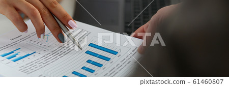 Female arm holding silver pen point in financial graph 61460807