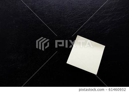 Stationery yellow stickers for inscription on a black leather isolated background. Blank sticker for reminder. Stationery yellow stickers for inscription on a black leather isolated background. Blank sticker for reminder. 61460932
