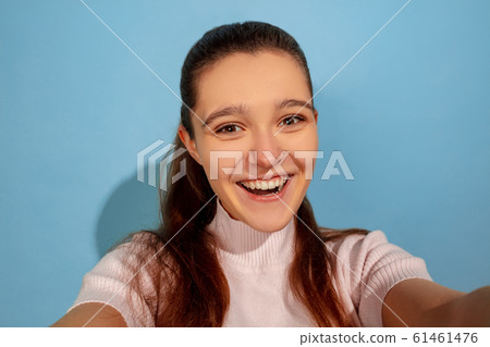 Caucasian teen girl portrait isolated on blue studio background Caucasian teen girl portrait isolated on blue studio background 61461476