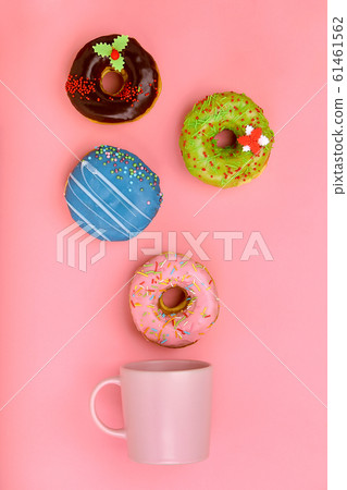 A mug from which sweet donuts fly out, on a pink background. Sweet and coffee donuts concept. colored on pink. Mock up for design. Copy space. 61461562