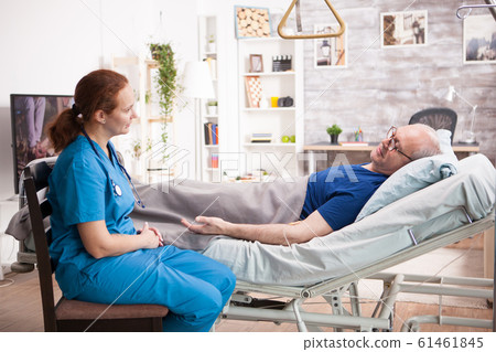 Senior man in nursing home talking with female nurse Senior man in nursing home talking with female nurse 61461845