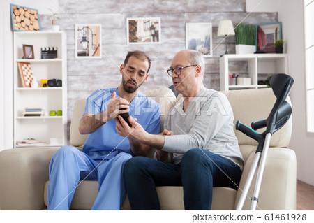 Young male nurse in nursing home holding phone 61461928