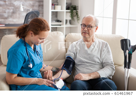 Female doctor reading blood pressure of old man 61461967