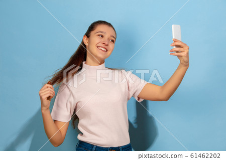 Caucasian teen girl portrait isolated on blue studio background Caucasian teen girl portrait isolated on blue studio background 61462202