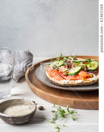 Healthy toast with cream cheese, salmon, fresh cucumber, capers, red onion, black pepper and pea sprouts on plate. Copy space 61463169