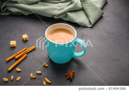 Traditional Indian masala tea chai in a blue cup. Cinnamon, anise, cardamom, sugar next to a black 61464366