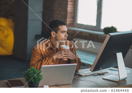 Serious young man sitting with a cup of coffee 61464448
