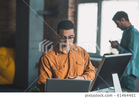 Smart diligent young man focusing on his work 61464481