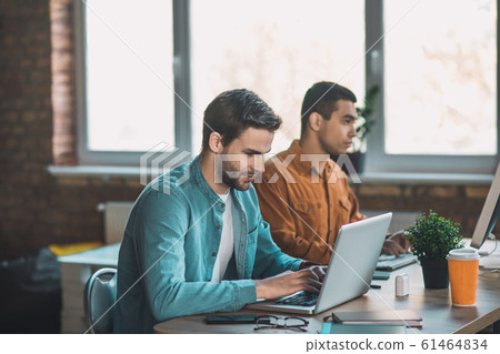 Handsome intelligent man concentrating on his work 61464834