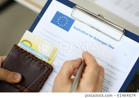 Male hands using pen and visa application 61464874