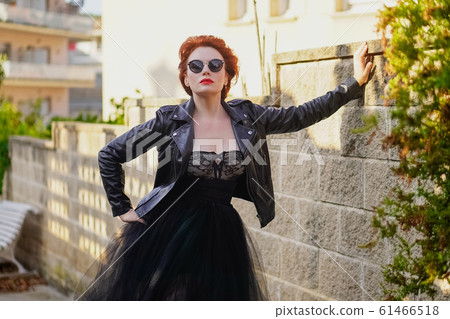 A bright confident beautiful red-haired woman in a black leather jacket, lace sexy dress and glasses A bright confident beautiful red-haired woman in a black leather jacket, lace sexy dress and glasses 61466518