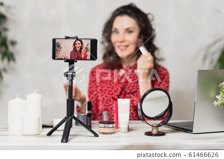 Influencer Young girl blogger talks about makeup. Woman recording video blog tells how to be beautiful. Bloger talks facial beauty treatments. Vloggre broadcasts how to use of cosmetic 61466626
