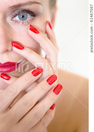 A beautiful young woman is touching her face with her fingers 61467087