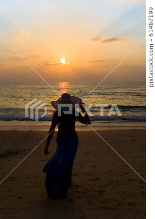 Silhouette of a lonely girl walking towards the sea.  61467199