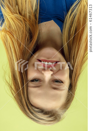 Inverted portrait of caucasian young woman on yellow studio background 61467313