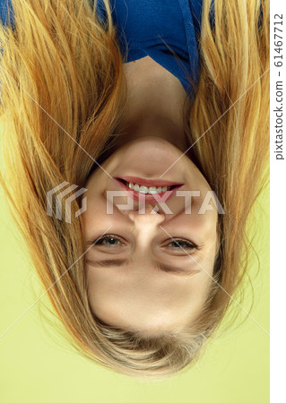 Inverted portrait of caucasian young woman on yellow studio background Inverted portrait of caucasian young woman on yellow studio background 61467712
