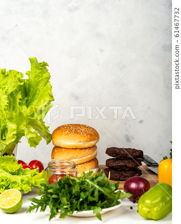 Big burgers with cutlet, cheese and herbs on white background in the kitchen. Big burgers with cutlet, cheese and herbs on white background in the kitchen. 61467732