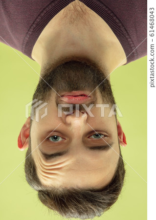 Inverted portrait of caucasian young man on yellow studio background 61468043