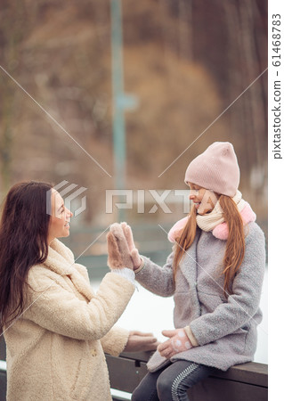 Little adorable girl with her mother skating on ice-rink 61468783