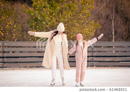Little adorable girl with her mother skating on ice-rink Little adorable girl with her mother skating on ice-rink 61468931