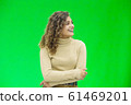 Hello everyone. Portrait of confident attractive and self-assured female looking to the side, smiling friendly over green background. 61469201