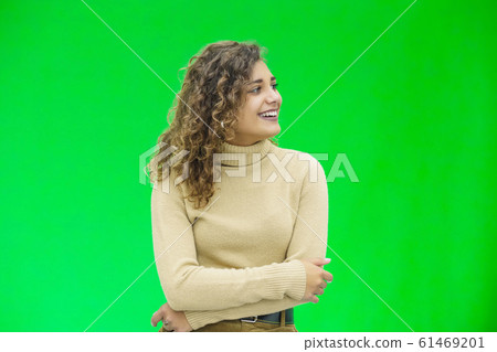 Hello everyone. Portrait of confident attractive and self-assured female looking to the side, smiling friendly over green background. Hello everyone. Portrait of confident attractive and self-assured female looking to the side, smiling friendly over green background. 61469201