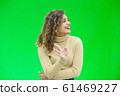 Hello everyone. Portrait of confident attractive and self-assured female waving hello, smiling friendly over green background. 61469227