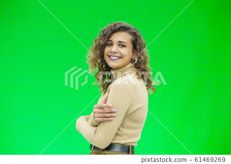 Happy young woman with a cute smile standing on green background with copy space. Happy young woman with a cute smile standing on green background with copy space. 61469269