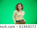 Glowing girl posing on green background, looking positive, smiling. 61469272