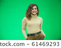 Glowing girl posing on green background, looking positive, smiling. 61469293