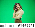 Portrait of gorgeous female model posing in white fashion clothes in studio over green background. 61469321
