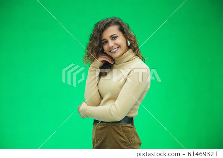 Portrait of gorgeous female model posing in white fashion clothes in studio over green background. Portrait of gorgeous female model posing in white fashion clothes in studio over green background. 61469321
