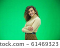 Portrait of gorgeous female model posing in white fashion clothes in studio over green background. 61469323