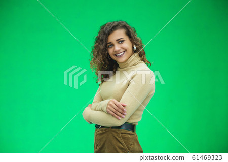 Portrait of gorgeous female model posing in white fashion clothes in studio over green background. Portrait of gorgeous female model posing in white fashion clothes in studio over green background. 61469323