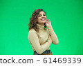 Portrait of gorgeous female model posing in white fashion clothes in studio over green background. 61469339