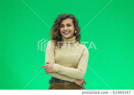 Portrait of a beautiful friendly african american woman with curly hairstyle and lovely smile isolated on a green background, her hands folded. Portrait of a beautiful friendly african american woman with curly hairstyle and lovely smile isolated on a green background, her hands folded. 61469347