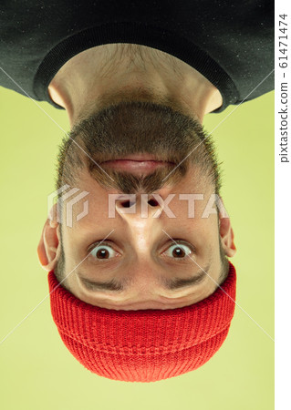 Inverted portrait of caucasian young man on yellow studio background 61471474