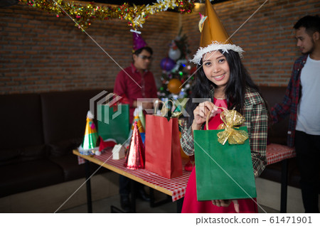 beautiful woman wear red dress and santa claus hat showing green gift bag on hand in restaurant. concept of Christmas party and New year party. beautiful woman wear red dress and santa claus hat showing green gift bag on hand in restaurant. concept of Christmas party and New year party. 61471901