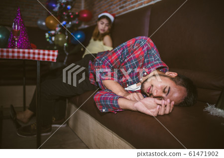 Asian man and women are very drunk sleeping on the couch after the party ended. concept of Xmas party, Christmas party and New year party celebration. 61471902