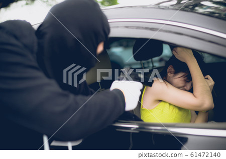 Criminal or Bandit wear black mask use gun point to woman in black car at the parking trying to rob money and hurting her 61472140