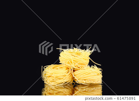 raw dry nest pasta with reflection on black raw dry nest pasta with reflection on black 61475891